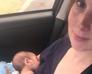 Mother breastfeeding newborn baby in car during bushfire emergency evacuation