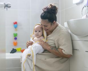 A mother and baby smile after baby's bath