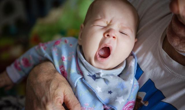 grandfather holds sleepy baby