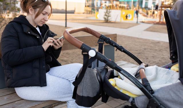 women looking at phone with pram