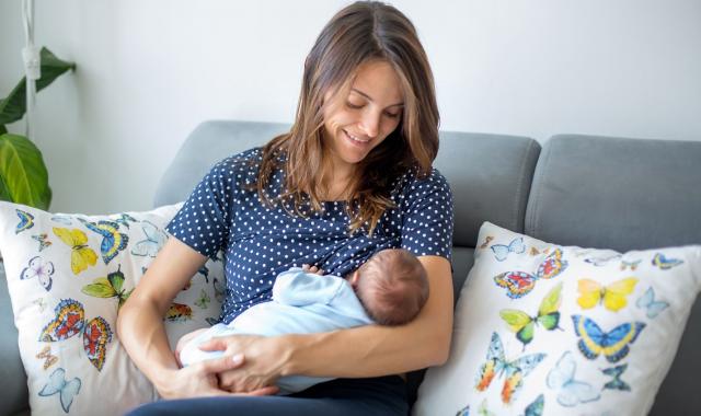 Mum sitting on couch breastfeeding