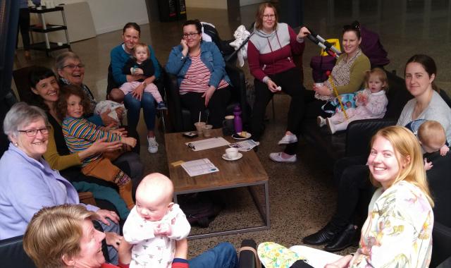 Group of women, babies and children sitting around the table.