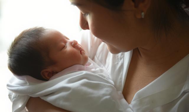 A woman holds her sleeping newborn baby