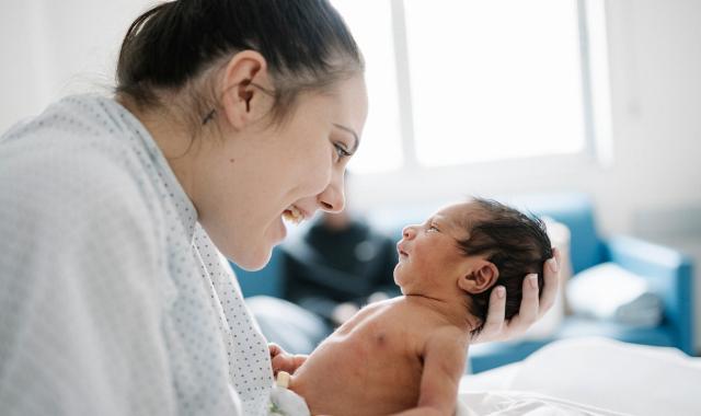 A mother smiles at her newborn baby