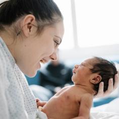 A mother smiles at her newborn baby