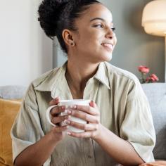 A woman smiles while holding a warm drink in a mug
