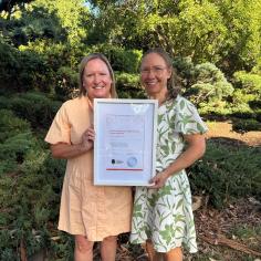 Two employees holding a framed BFW Certificate