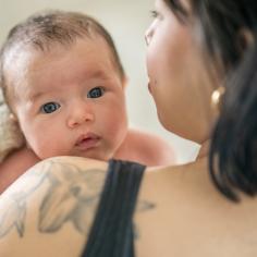 A baby looks over their mother's shoulder