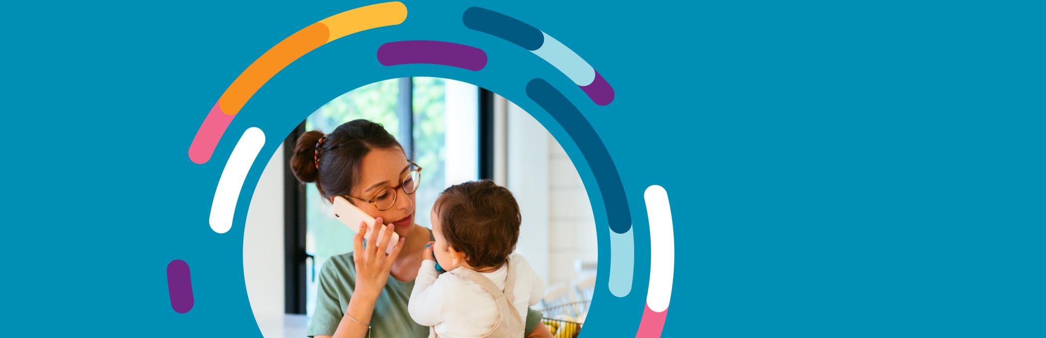 A woman holds her baby while she speaks on the phone