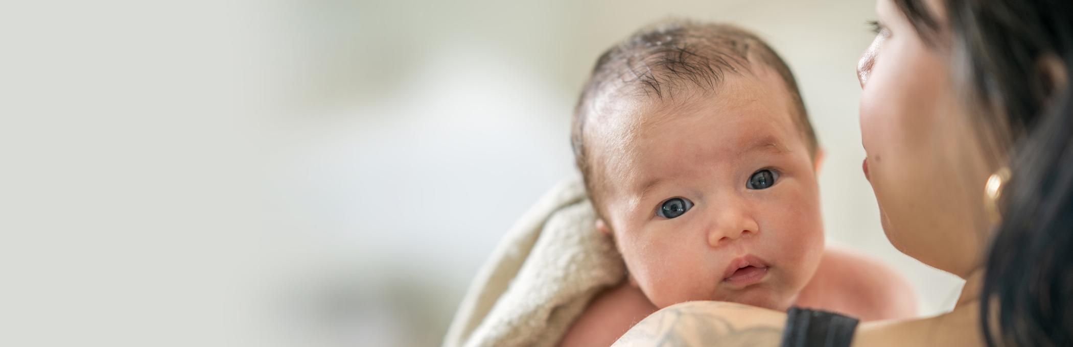 A baby looks over their mother's shoulder